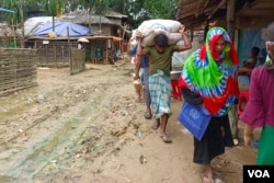 A Rohingya man carryies food rations in a refugee camp in Cox’s Bazar, Bangladesh, on July 22, 2023. The Bangladesh government does not allow Rohingya to work outside the camps. They are solely dependent on food rations provided by the U.N. food agency. (Noor Hossain for VOA)