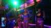 FILE - Dancers wearing face shields dance inside a bar at Patpong nightlife and sex trade district in Bangkok, July 9, 2020.