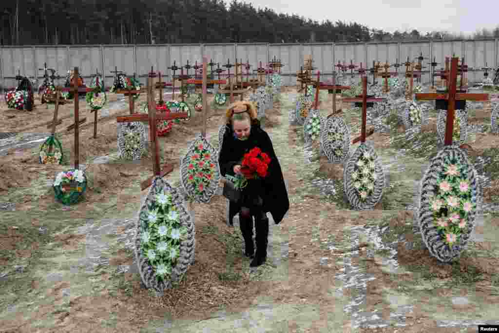 Una mujer coloca flores en las tumbas de personas no identificadas en el cementerio de la ciudad, a las afueras de Kiev, Ucrania 24 de febrero 2023. &nbsp;