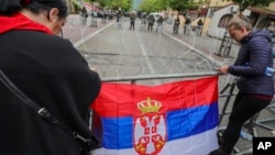 Women attach a Serbian flag to fence in front of the city hall during a protest in the town of Zvecan in northern Kosovo, May 31, 2023.
