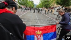 Žene kače srpsku zastavu na ogradu tokom protesta u Zvečanu, 31. maj 2023.