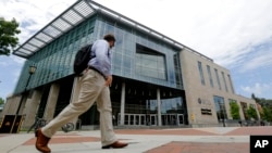 FILE - In this June 20, 2019, photo, a Virginia Commonwealth University student walks past the library at the school in Richmond, Va. 