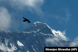 FILE - A bird flies with Mount Everest seen in the background from Namche Bajar, Solukhumbu district, Nepal, May 27, 2019. (AP Photo/Niranjan Shrestha, File)