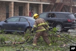 Seorang petugas pemadam kebakaran membersihkan puing-puing pasca badai hebat yang melanda wilayah Slidell, Louisiana, Rabu, 10 April 2024. (AP/Gerald Herbert)