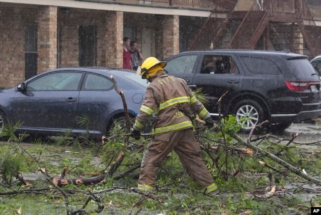 Seorang petugas pemadam kebakaran membersihkan puing-puing pasca badai hebat yang melanda wilayah Slidell, Louisiana, Rabu, 10 April 2024. (AP/Gerald Herbert)