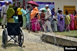 Polisi berjaga saat para pemilih antre untuk memberikan suaranya di TPS saat pemungutan suara ulang di 11 TPS, di Imphal, Manipur, India, 22 April 2024. (REUTERS/Stringer)