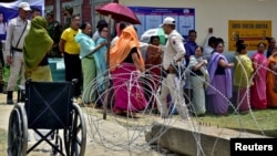 Petugas polisi berjaga saat para pemilih mengantre untuk memberikan suara di Imphal, Manipur, India, 22 April 2024. (Foto: Reuters)