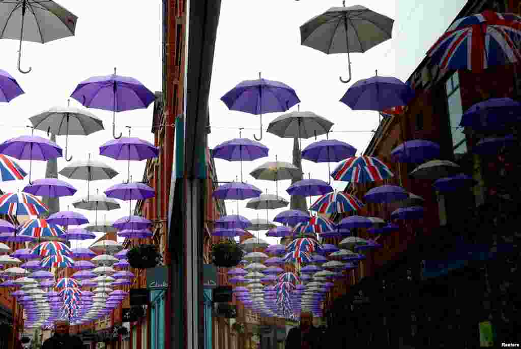 A man walks under a display of umbrellas in Durham, Britain.