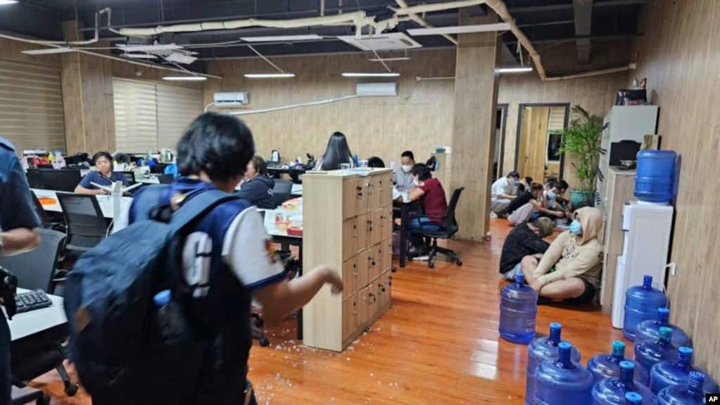 FILE - In this photo provided by the Philippine National Police Anti-Cybercrime Group, police enter an office they raided in Las Pinas, Philippines, June 27, 2023. Journalists reporting on illicit activity connected to scam centers in Cambodia say they face security risks. 