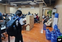 FILE - In this photo provided by the Philippine National Police Anti-Cybercrime Group, police walks inside one of the offices they raided in Las Pinas, Philippines, June 27, 2023.