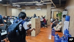 FILE - In this photo provided by the Philippine National Police Anti-Cybercrime Group, police enter an office they raided in Las Pinas, Philippines, June 27, 2023. Journalists reporting on illicit activity connected to scam centers in Cambodia say they face security risks. 
