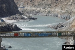 FILE - Jembatan dengan bendera China dan Pakitan di atas Sungai Indus, di lokasi Bendungan Dasu (Proyek Pembangkit Listrik Tenaga Air Dasu) di distrik Kohistan provinsi Kyber Pakhtunkhwa, dekat Dasu, Pakistan, 6 Oktober 2023. (REUTERS/ Akhtar Soomro)