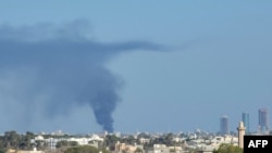 Smoke billows amid clashes between armed groups affiliated with Libya's Tripoli-based Government of National Unity (GNU) in the Libyan capital on August 15, 2023.