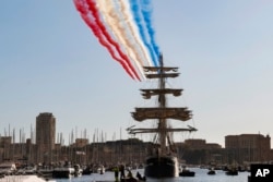 The French acrobatic flying team Patrouille de France flies over the French 19th-century three-mast ship Belem during the torch arrival ceremony in Marseille, southern France, May 8, 2024.
