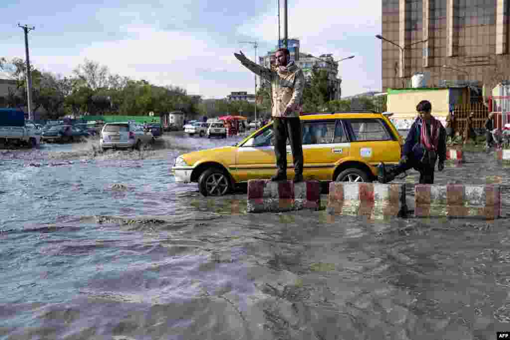 A traffic policeman gestures whilst on duty amid a flooded road in Kabul, Afghanistan.