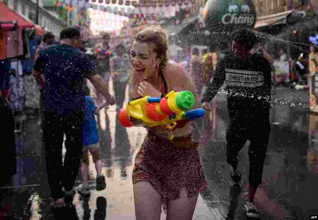 A woman is soaked as she runs down the street as revelers take part in a water fight on Khao San road on the eve of Thai New Year, locally known as Songkran, in Bangkok, Thailand.