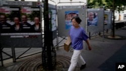 A woman walks past campaign boards for the upcoming parliamentary elections in Paris, June 27, 2024.