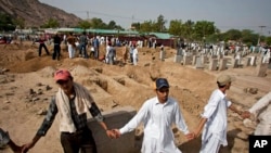 FILE - People from the Muslim Ahmadi community stand guard as others prepare to bury victims of attack by Islamic militants, in Rubwah, Pakistan, 29, 2010. The Ahmadis have recorded nearly three dozen attacks on their places of worship so far in 2023.