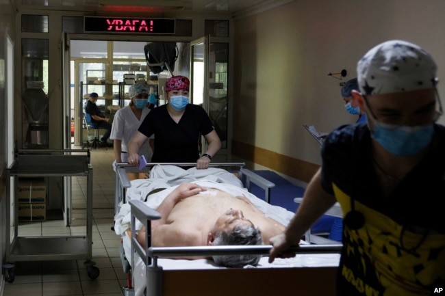 Medical workers transport a Ukrainian serviceman on the stretcher before a surgery operation at the military hospital in Kyiv, Ukraine, on Thursday, May 5, 2023. (AP Photo/Alex Babenko)