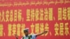Seorang polisi tampak berdiri di depan papan iklan propaganda yang berbunyi "pemeliharaan aturan hukum di Xinjiang" yang ditulis dalam Bahasa Mandarin dan Uyghur dan terpasang di sebuah jalan di prefektur Kashgar, Xinjiang, pada 19 Juli 2023. (Foto: AFP/Pedro Pardo)