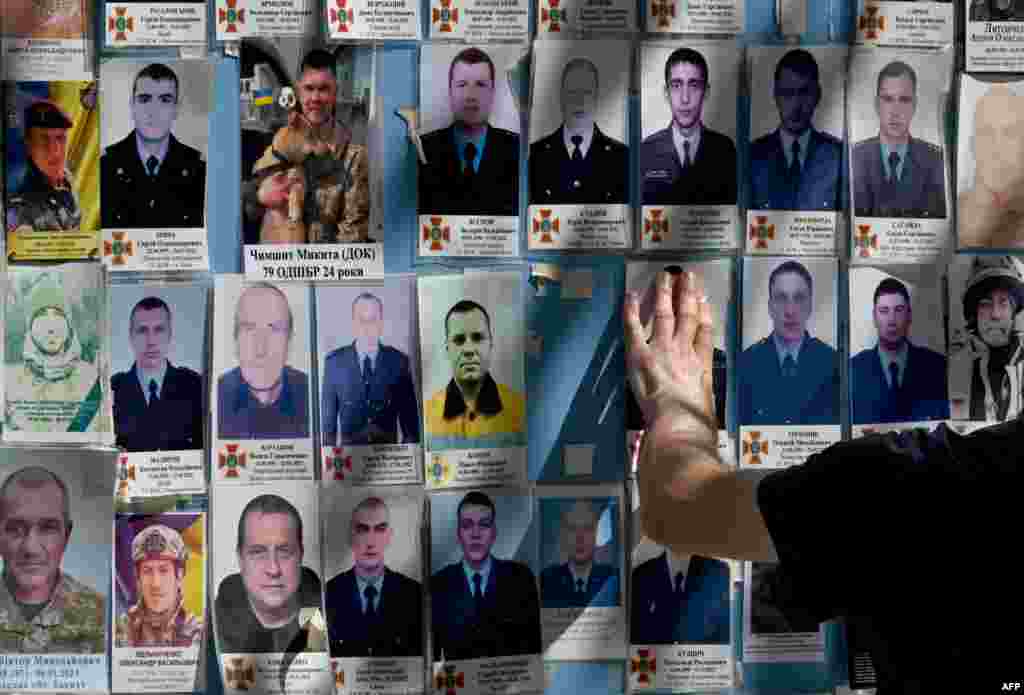 A wounded Ukrainian serviceman touches pictures of his fallen comrades on the Memory Wall of Fallen Defenders of Ukraine in Kyiv, amid the Russian invasion of Ukraine.