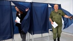A woman and a serviceman leave a voting area at a polling station during Russia-organized elections in Donetsk, capital of Ukraine's mostly Russian-occupied Donetsk region, Sept. 10, 2023. 