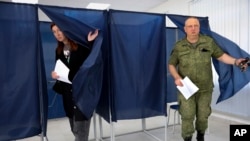 A woman and a serviceman leave a voting area at a polling station during Russia-organized elections in Donetsk, capital of Ukraine's mostly Russian-occupied Donetsk region, Sept. 10, 2023.