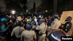 Law enforcement officers try to clear an area near an encampment by supporters of Palestinians in Gaza, on the campus of the University of California, Los Angeles (UCLA), in Los Angeles, California, in the early morning hours of May 1, 2024.