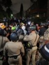 Law enforcement officers try to clear an area near an encampment by supporters of Palestinians in Gaza, on the campus of the University of California, Los Angeles (UCLA), in Los Angeles, California, in the early morning hours of May 1, 2024.