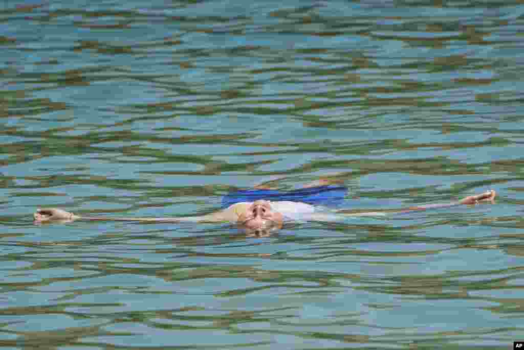 A person floats to cool off at Castaic Lake as temperatures rise, July 8, 2024, in Castaic, California.