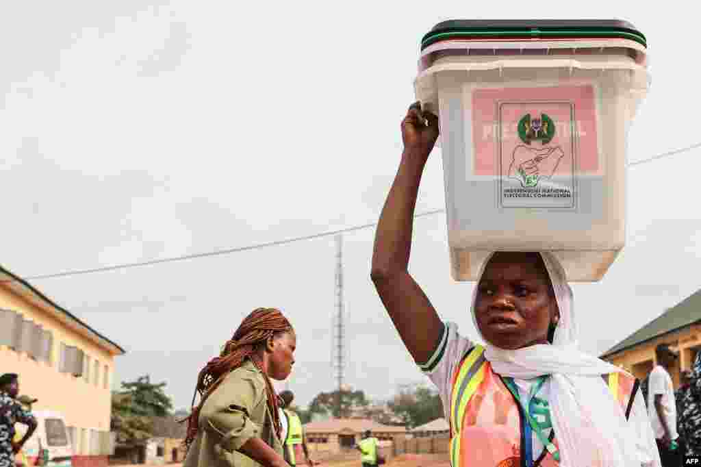 An Independent National Electoral Commission (INEC) official carries ballot boxes on her head to be set up at a polling station in Ibadan on February 25, 2023.