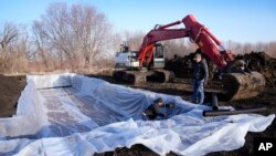 FILE - Workers prepare to install wood chips in a bioreactor trench in a farm field, March 28, 2023, near Roland, Iowa. Systems called bioreactors and streamside buffers help filter nitrates from rainwater before it can reach streams and rivers. 