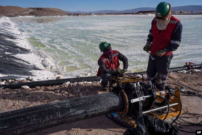 FILE - Workers perform maintenance at the pools where brine is evaporated at the lithium extraction plant facilities of the SQM Lithium company near Peine, Chile, Thursday, April 18, 2023. (AP Photo/Rodrigo Abd)