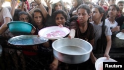 Anak-anak Palestina berkumpul untuk mengambil makanan di dapur amal di tengah kelangkaan pangan, seiring berlanjutnya konflik Israel-Hamas, di Jalur Gaza utara, 18 Juli 2024. (Foto: Mahmoud Issa/Reuters)