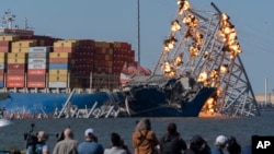 Explosive charges are detonated to bring down sections of the collapsed Francis Scott Key Bridge resting on the container ship Dali on May 13, 2024, in Baltimore. 