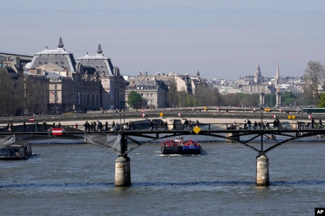 FILE - Barges travel along the River Seine in Paris, Wednesday, April 5, 2023. (AP Photo/Christophe Ena)