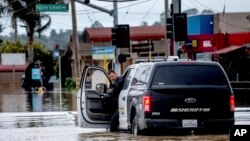 Un ayudante del alguacil revisa su camioneta mientras conduce a través de las inundaciones en la comunidad de Pájaro en el condado de Monterey, California, el lunes 13 de marzo de 2023. (Foto AP/Noah Berger)