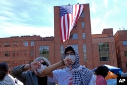 Protesters react as a giant American flag is unfurled on Lisner Hall on the campus of George Washington University in Washington, May 3, 2024, as demonstrators protest against the Israel-Hamas war.