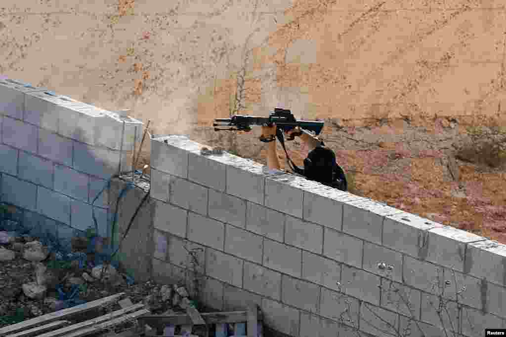 A Palestinian militant shoots at Israeli forces as they take up position near a house where a Palestinian militant is hiding during a raid near Tubas in the Israeli-occupied West Bank.