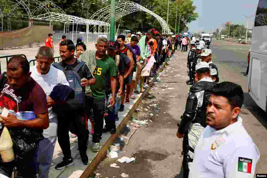 Miembros de la Guardia Nacional Mexicana hacen fila, mientras los migrantes esperan para abordar un autobús, antes de ser trasladados a Tuxtla Gutiérrez, para continuar con sus trámites y obtener el Formulario Migratorio Múltiple de 45 días que les permitirá transitar por México y llegar al norte frontera, en Tapachula, México 12 de mayo de 2023.