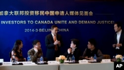 资料照：北京的一名移民咨询人员在一个记者会上与参会者交谈。（2014年3月4日）
