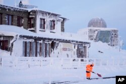 Seorang pekerja kereta api membersihkan jalur salju di gunung tertinggi 'Brocken' setinggi 1.142 meter (3.743 kaki) di Jerman utara di pegunungan Harz dekat Schierke, Jerman, Rabu, 17 Januari 2024. (AP Photo/Matthias Schrader)