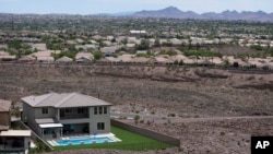 FILE - A home with a swimming pool abuts the desert on the edge of the Las Vegas valley in Henderson, Nevada, July 20, 2022.
