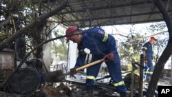 Petugas pemadam kebakaran di luar rumah yang hancur di pinggiran kota Chalandri, Athena, setelah kebakaran hutan besar menghanguskan pinggiran utara ibu kota Yunani, Selasa, 13 Agustus 2024. (Michael Varaklas/AP)