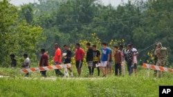 Migrantes caminan en fila después de acercarse a un funcionario cerca del Río Grande tras cruzar la frontera entre Texas y México, el 11 de mayo de 2023, en Brownsville, Texas.