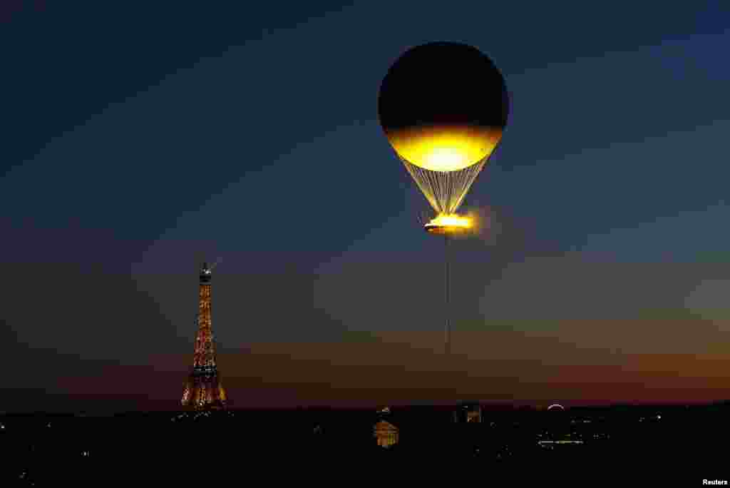 The Olympic cauldron and the Eiffel Tower are seen from the Musee des Arts Decoratifs after sunset in Paris, France, Aug. 5, 2024.