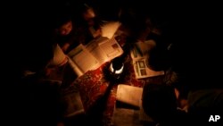 کودکان افغان در دور یک چراغ تیلی سبق می‌خوانند