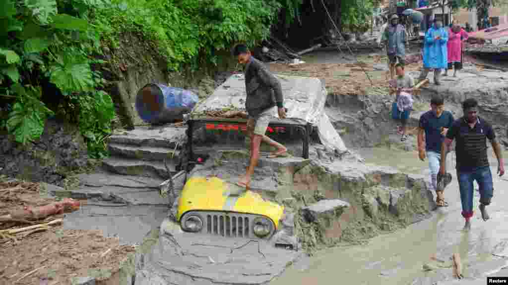 People walk along a street as a jeep is buried in the mud due to the flood at Teesta Bazaar in Kalimpong District, West Bengal, India.&nbsp;REUTERS/Brihat Rai