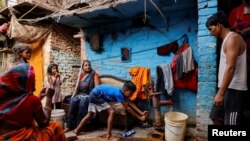 A boy fills water in a container using a hand pump on a hot summer day during a heatwave in New Delhi, India.