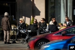 FILE - Orang-orang menikmati hari yang cerah sambil duduk di teras sebuah kafe di Helsinki, Finlandia, Senin, 3 April 2023. (AP/Sergei Grits)